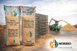 Norbio Premium Pellets træpiller i sække foran stablede poser og flishugger